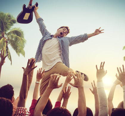 Young Man with a Guitar Performing on a Beach Concert